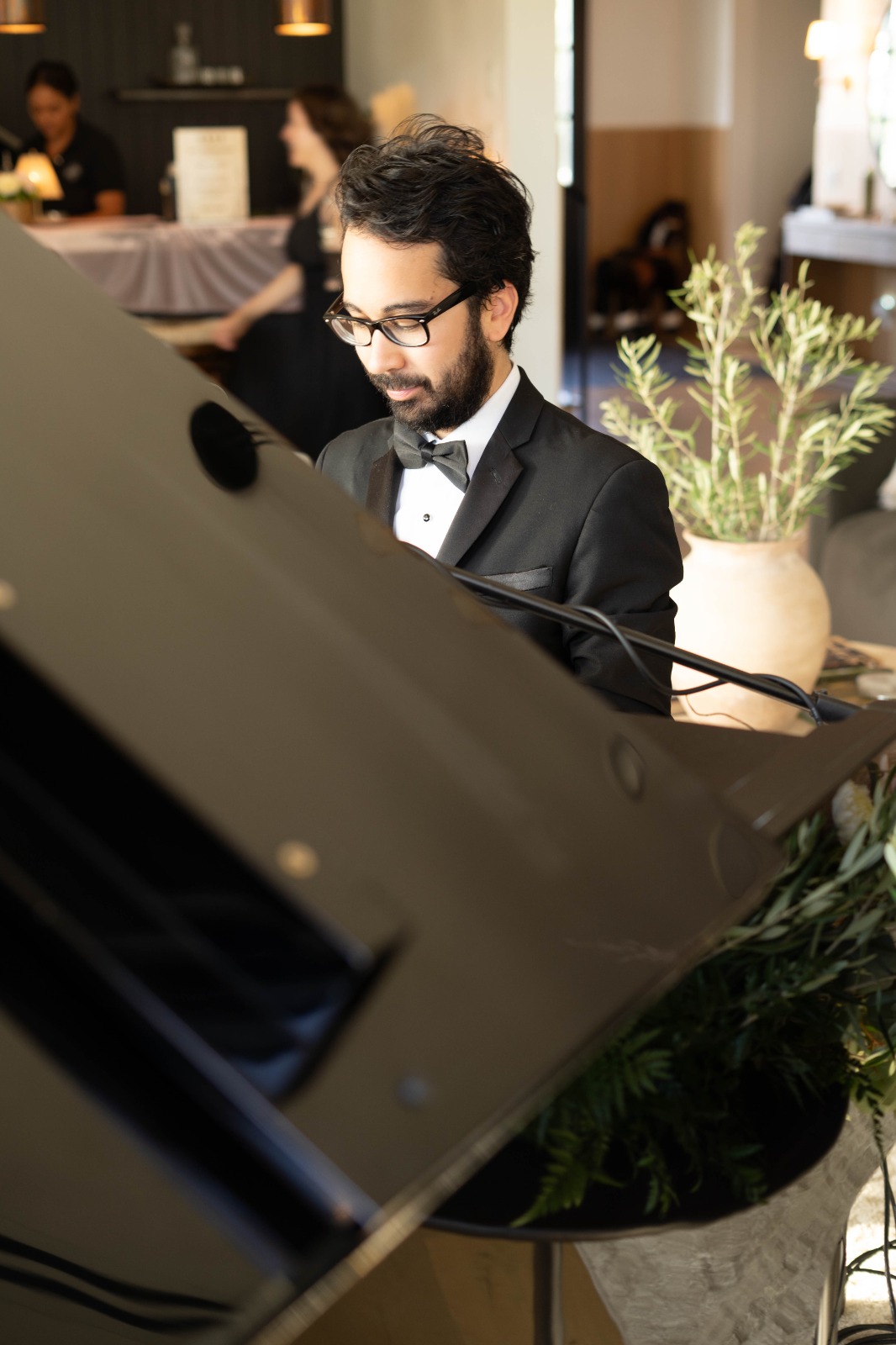 Steven in black tie playing a grand piano